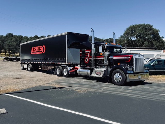 Black Kenworth with an Arbiso curtain van trailer