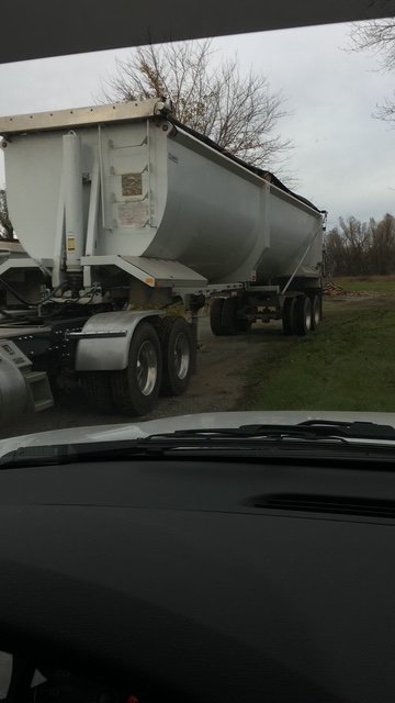 High side demo end-dump trailer behind a tractor, seen from a truck cab