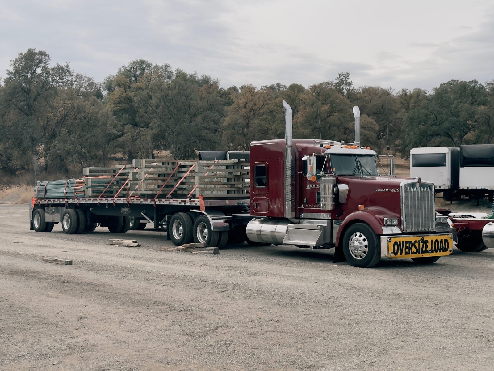 Maroon Kenworth with a loaded flatbed trailer