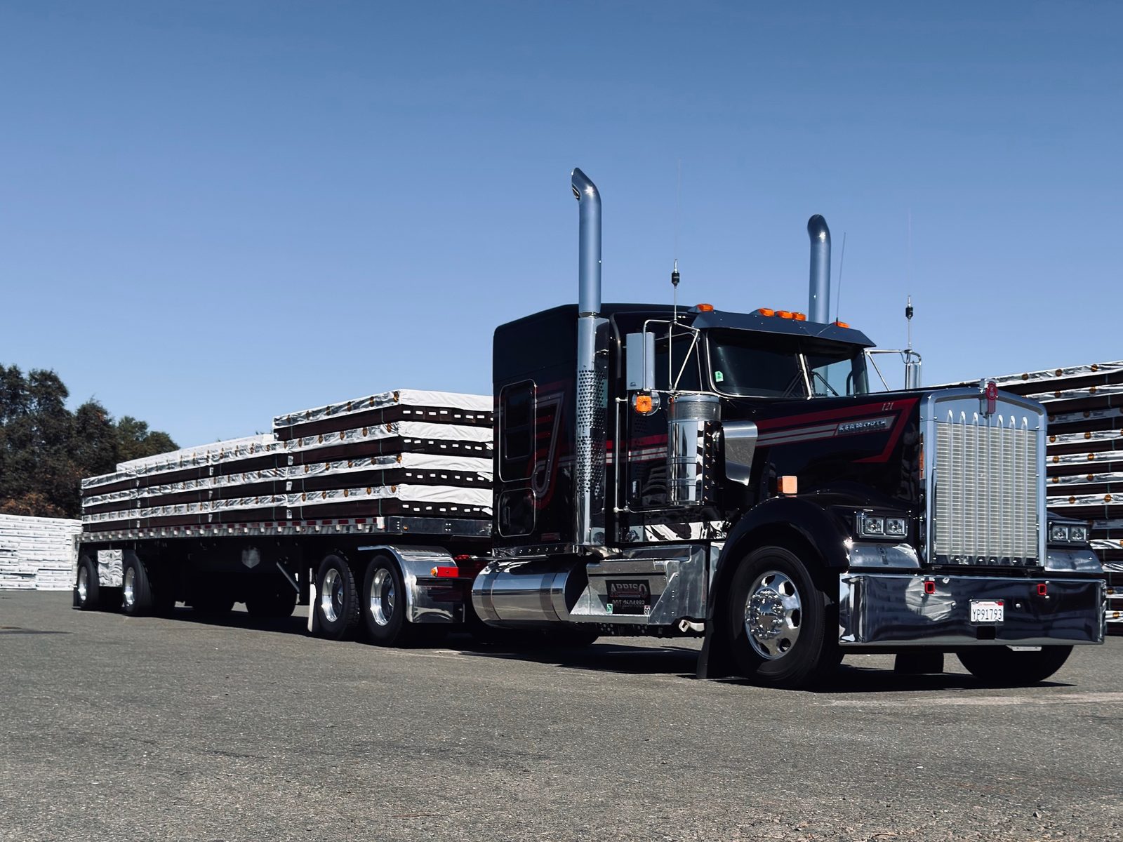 Black Kenworth with a loaded flatbed trailer