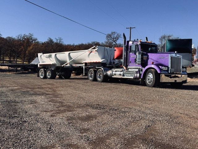 Tractor with an end-dump trailer in a gravel yard