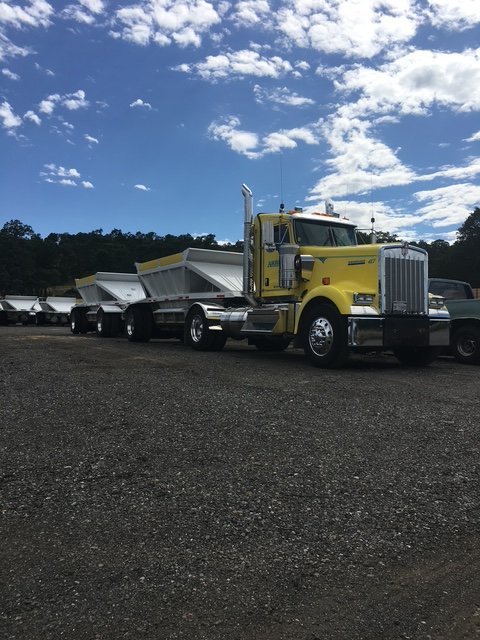 Yellow tractor with double bottom-dump trailers