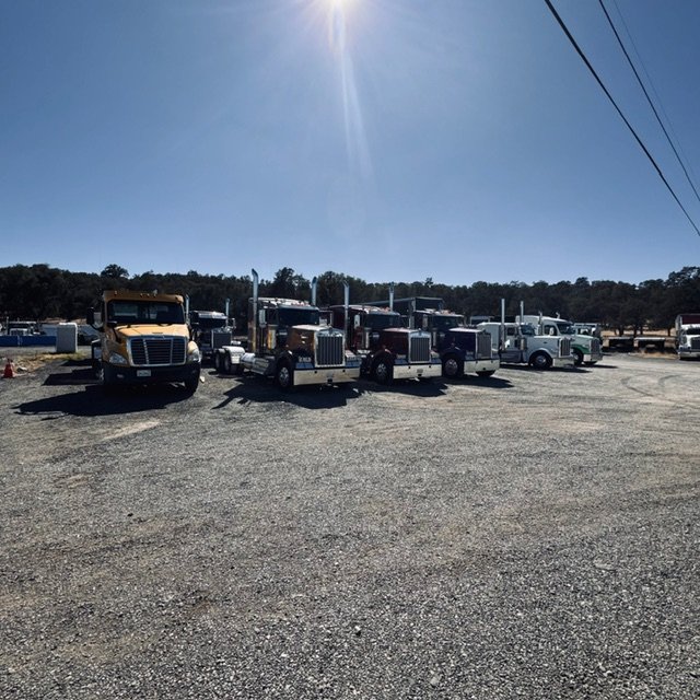 Row of trucks parked in a gravel lot
