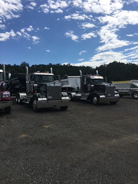 Black tractors parked in a row in a gravel yard